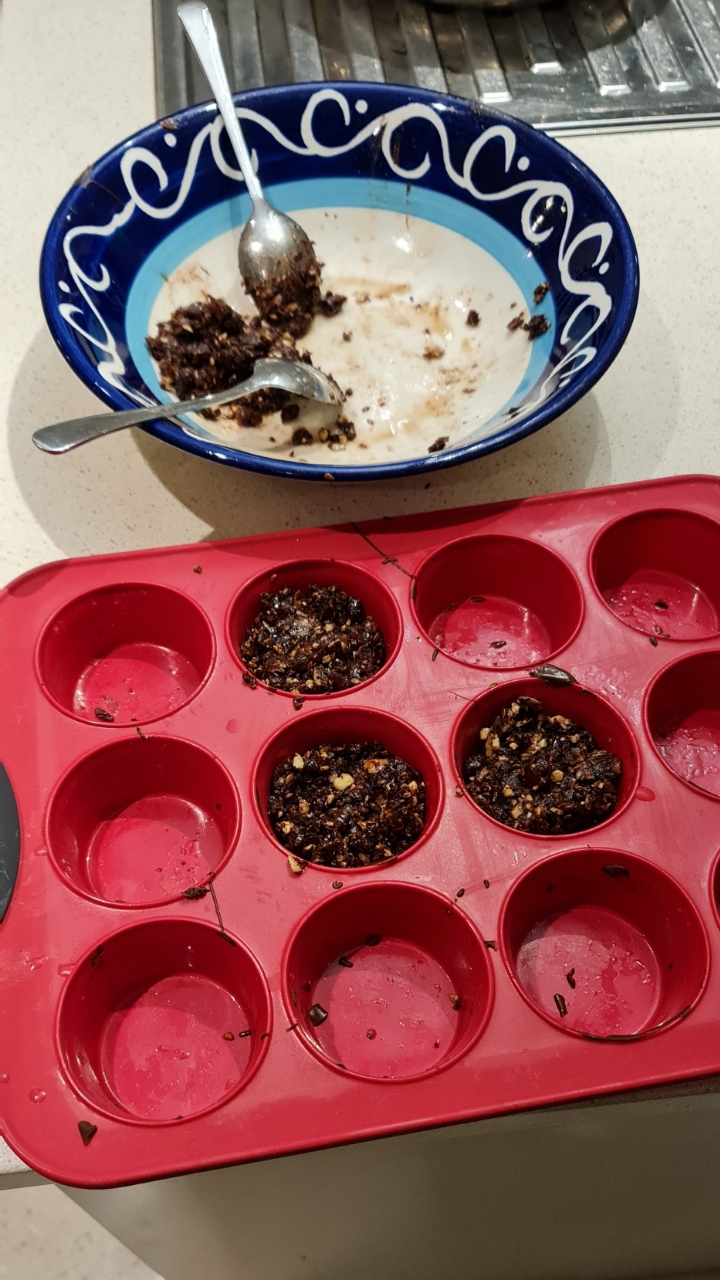 Silicone muffin tray part-filled with the fruit and seed mixture