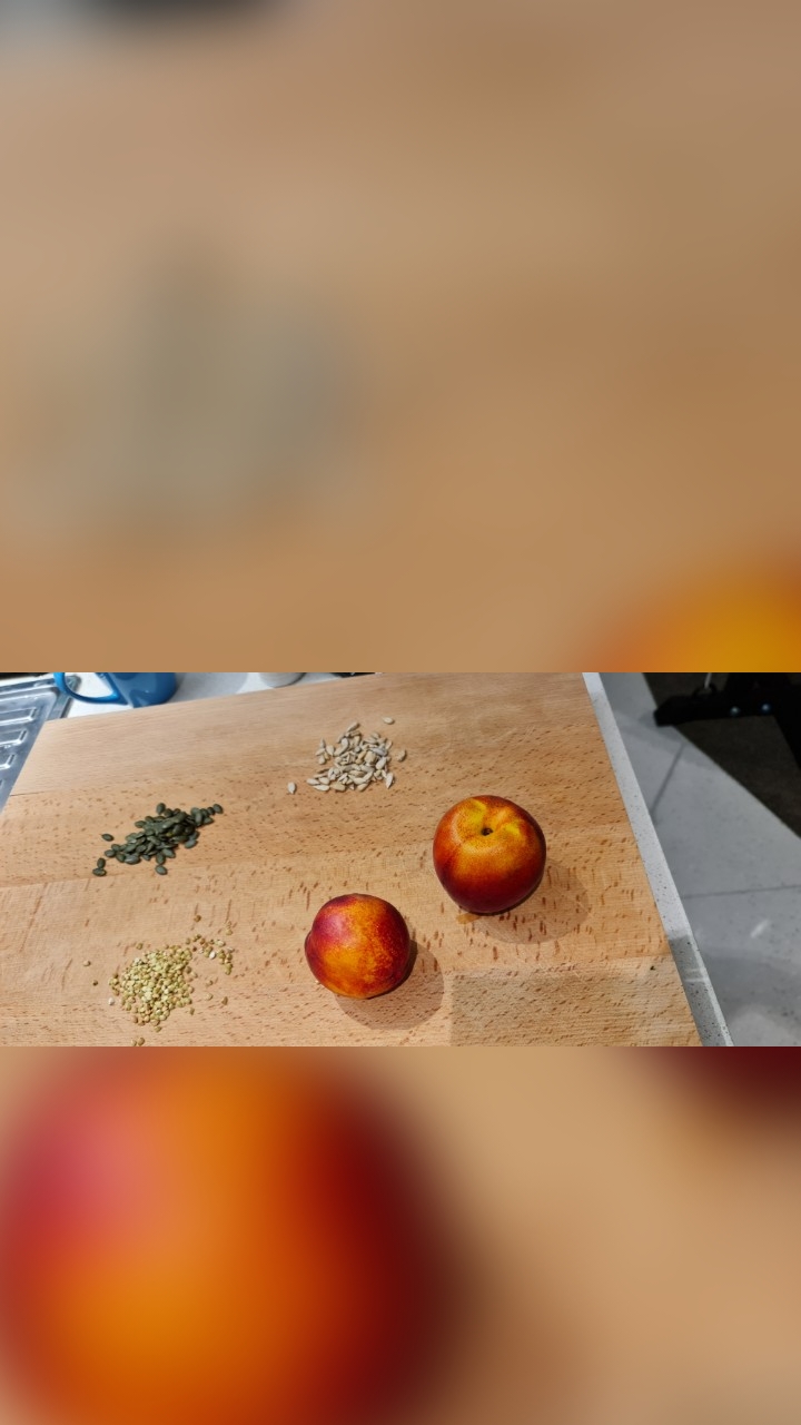Two whole nectarines on a board with small piles of seeds